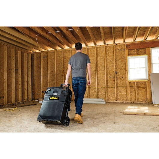 Photo of person pulling STANLEY 020800R mobile toolbox through unfinished room at construction site.