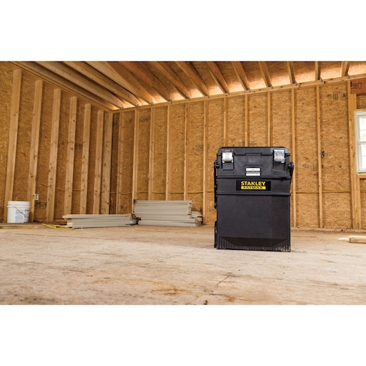 Photo of STANLEY 020800R black rolling tool chest in an unfinished wooden construction site.