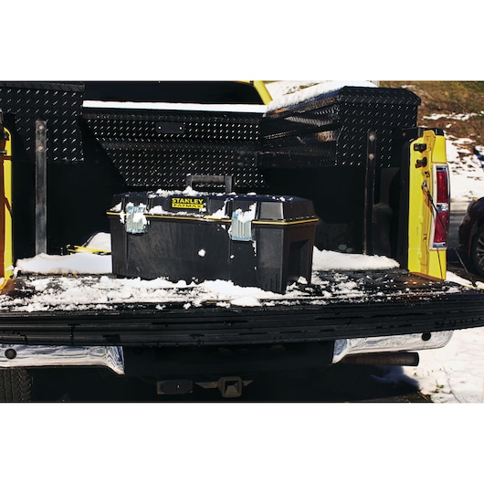 STANLEY 028001L toolbox on snowy truck tailgate, black with yellow accents, outdoor setting.