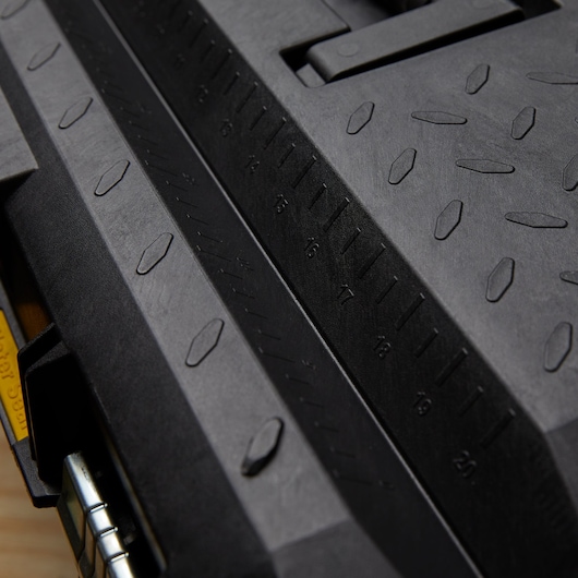 Photo of STANLEY 028001L photography, close-up of black plastic tool box surface with molded ruler markings.
