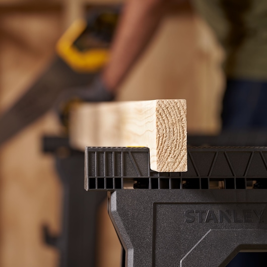 STANLEY 060864R photography of a black saw horse holding a light wood beam, close-up angle.