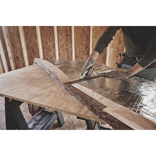 STANLEY 10-788 utility knife cutting insulation on plywood table, close-up photography.