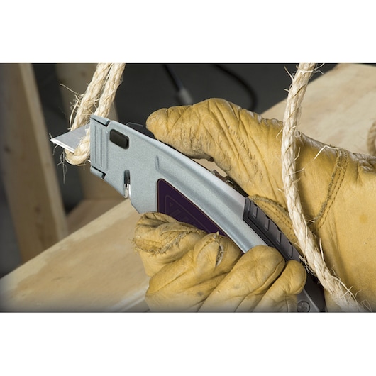 STANLEY 10-788 utility knife cutting rope, close-up of gloved hand holding the tool.