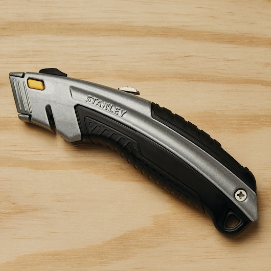 STANLEY 10-788 utility knife, silver and black, photographed from the side on a wooden surface.