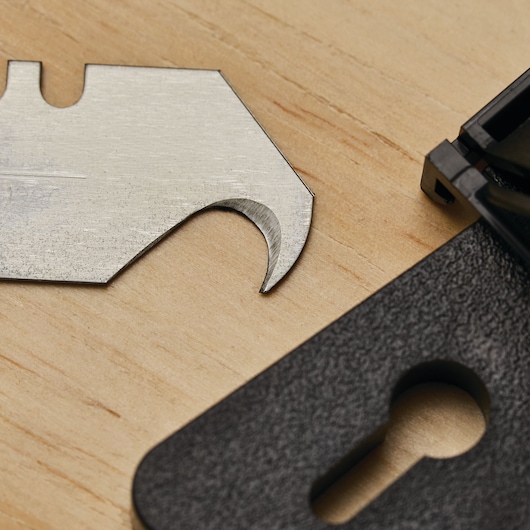 STANLEY 11-983L utility hook blade close-up on wood surface, partial black case visible