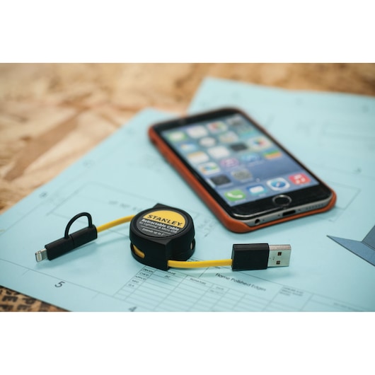 STANLEY 1311607ST1 retractable USB charging cable with yellow cord shown on blueprint next to smartphone.