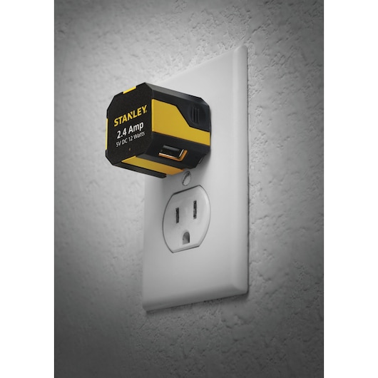 STANLEY 1319591ST2 USB wall adapter, yellow and black, plugged into electrical outlet, front angle.