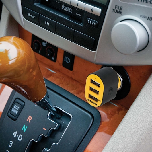 Stanley 1410414ST2 USB car charger plugged into vehicle console, yellow and black, side angle.