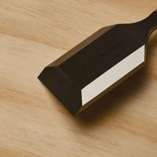 STANLEY 16-981 chisel blade close-up on light wood surface, showing sharp beveled edge.