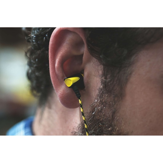 STANLEY 1909510ST2 yellow and black wired earplug in ear, close-up view, photography product.