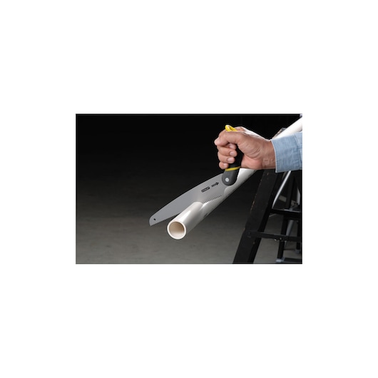 STANLEY 20-092 hand saw cutting white PVC pipe, close-up side view, black and yellow handle visible.