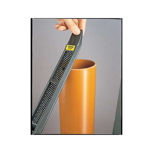 STANLEY 21-295 hand rasp file smoothing orange plastic pipe, close-up angle.