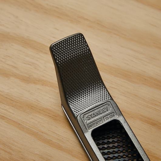 STANLEY 21-296 Surform planer tool with textured metal surface on wood background, closeup angle.