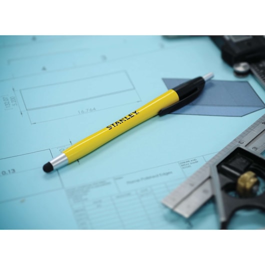 STANLEY 2151055ST2 yellow stylus pen on blue technical drawing with ruler and caliper, photo closeup.