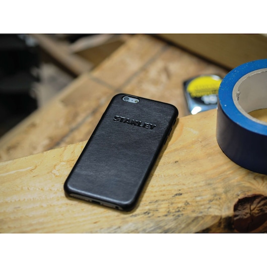 STANLEY 2159564ST2 black phone case on wooden surface, tape roll and tools in background.