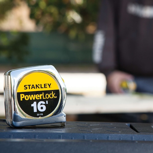 STANLEY 33-116 tape measure with chrome case and yellow-black label, photography with outdoor background.