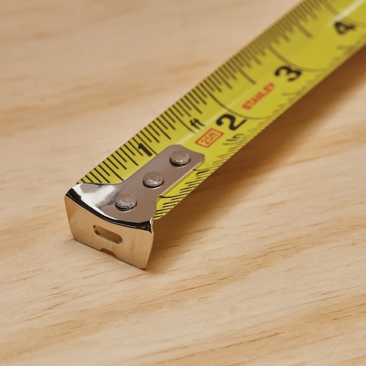 STANLEY 33-425 yellow tape measure close-up on wood surface, steel tip, photography category.