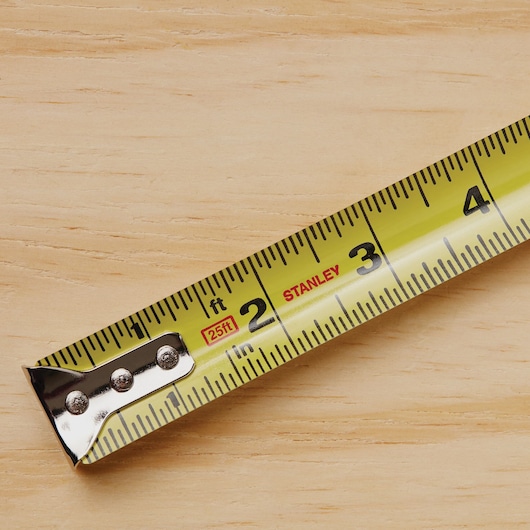 STANLEY 33-425 yellow tape measure close-up on wood surface, showing inch and foot markings.