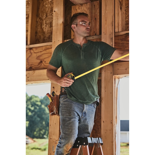 STANLEY 33-725 tape measure held by worker in construction setting, outdoor background, category: Photography.