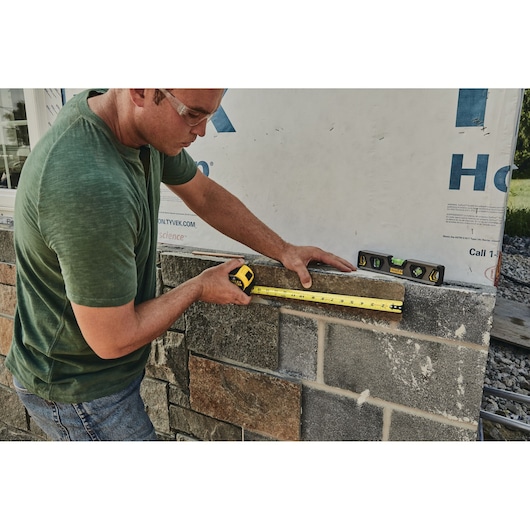 STANLEY 33-725 tape measure in use on masonry wall, photo of measuring process.