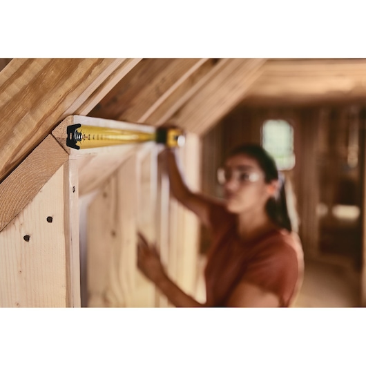 STANLEY 33-725 tape measure extended against wooden beams in a construction setting.