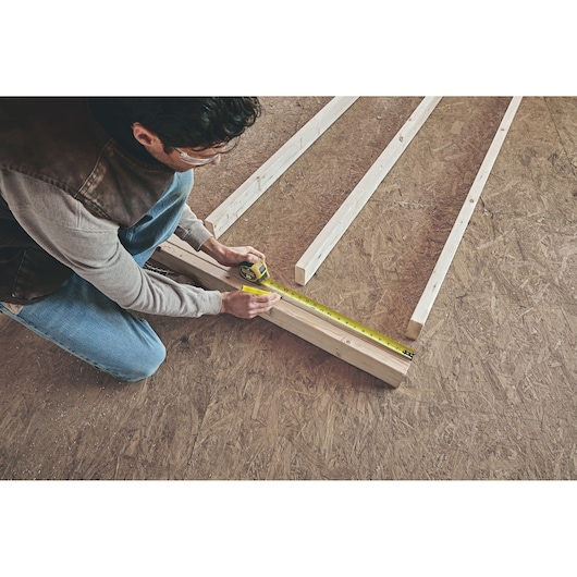 STANLEY 33-725 tape measure used to measure wood beams on workshop floor, photo from above.