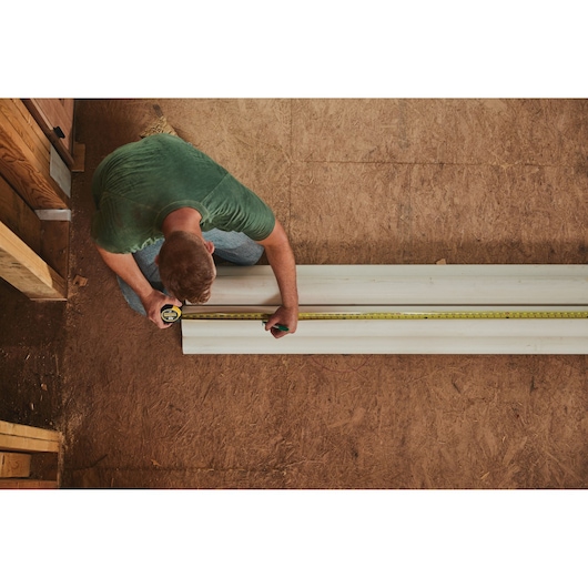 Photo of STANLEY 33-725 tape measure used to measure a white board in a construction setting.