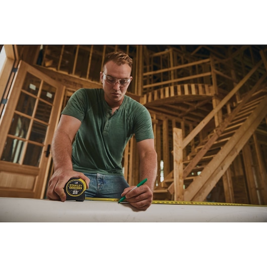 Stanley 33-725 tape measure used for marking wood in a home construction setting, product photography.