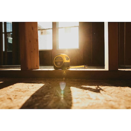 STANLEY FATMAX 33-725 tape measure on construction site floor, sunlight streaming through windows.