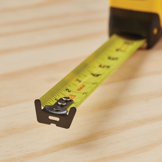 STANLEY 33-725 yellow tape measure extended on wood surface, close-up photo of measuring blade.