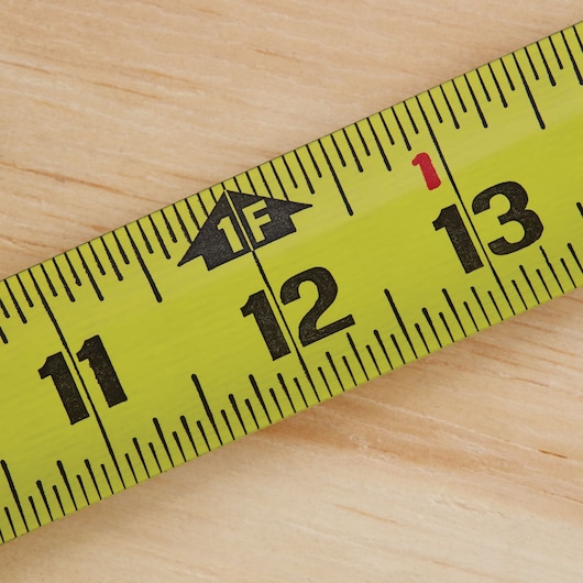 Photo of STANLEY 33-725 tape measure close-up on wood, showing yellow blade and black inch markings.