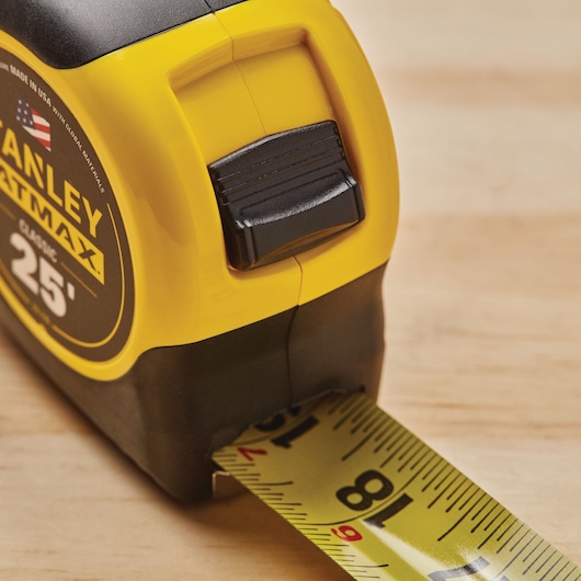 Photo of STANLEY 33-725 tape measure, yellow and black casing, partially extended on wood surface.
