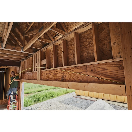STANLEY 33-730 tape measure used to measure a wooden frame in a construction site, outdoor scene.