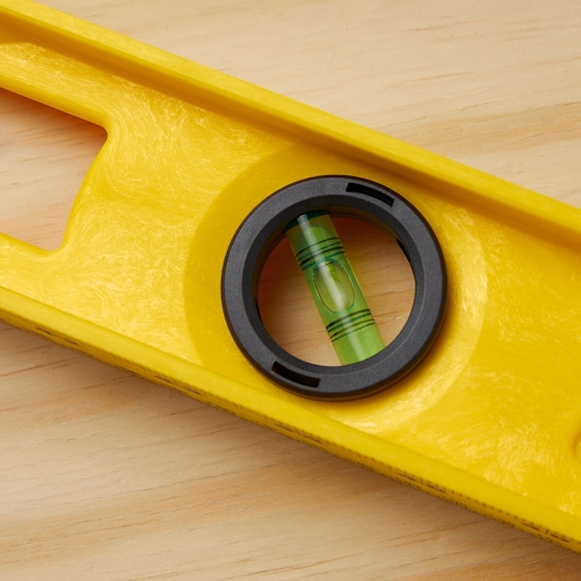 STANLEY 42-470 yellow spirit level close-up on wood surface, showing green bubble vial and black frame.