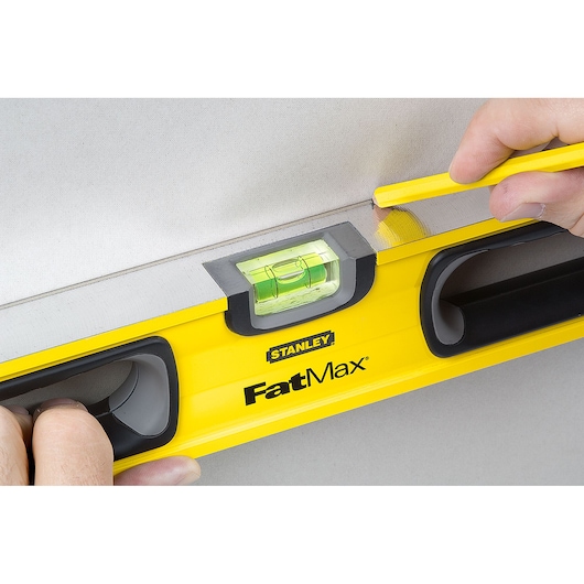 STANLEY 43-524 FatMax level photography, close-up of yellow hand tool with bubble vial, pencil marking line.