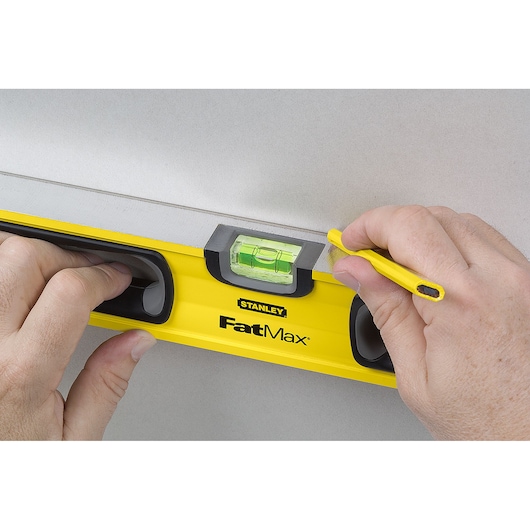 Photo of STANLEY 43-524 FatMax level tool held against wall for marking, shown from front angle.