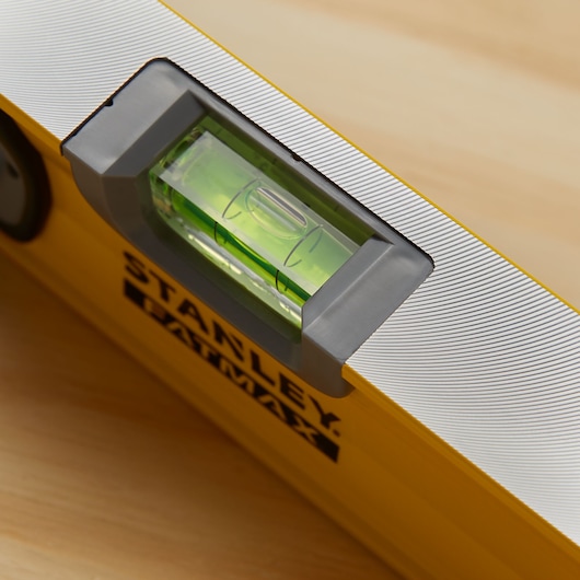 STANLEY 43-524 spirit level close-up showing green vial and yellow body on wood surface.
