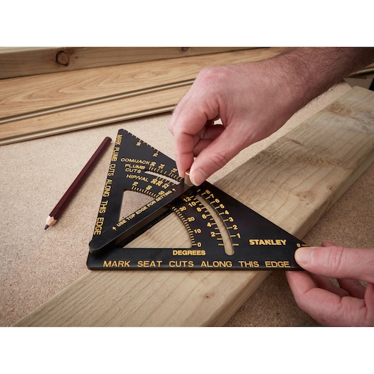 STANLEY 46-053 photography of black speed square with yellow markings on wood, hands setting angle, pencil nearby.