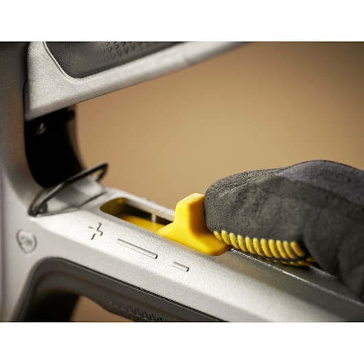 STANLEY FMHT70100 photography of close-up yellow adjustment lever on staple gun held by gloved hand.