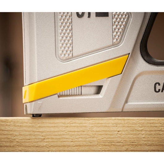 STANLEY FMHT70100 photography of stapler tool in close-up, silver with yellow accent, on wood surface.