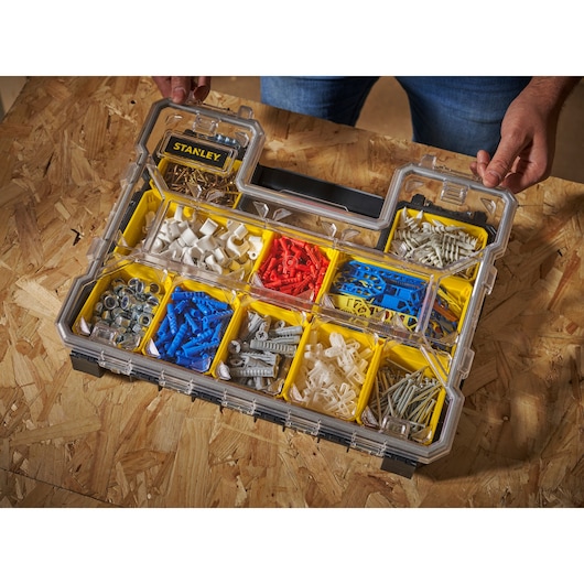 STANLEY FMST14820 organizer with clear lid holding assorted wall anchors and hardware in yellow compartments, angled top view.