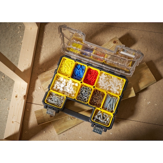STANLEY FMST14820 organizer box with yellow compartments filled with assorted hardware, open on a workshop floor.