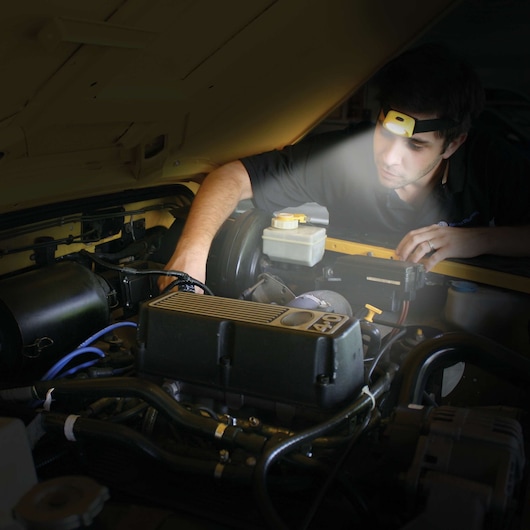 STANLEY HL2PKS headlamp used for hands-free lighting while working on a car engine, close-up view.