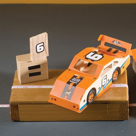 STANLEY OK002-SY photography of orange race car model with number 6 on wooden platform.
