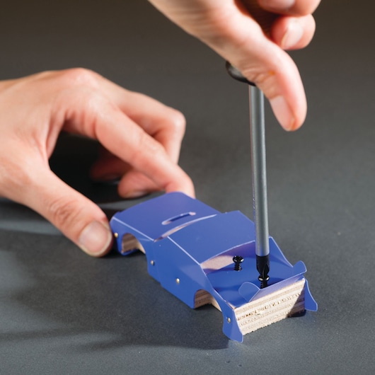 STANLEY OK013-SY woodworking jig tool, blue, being used to guide a screw into wood, angled view.