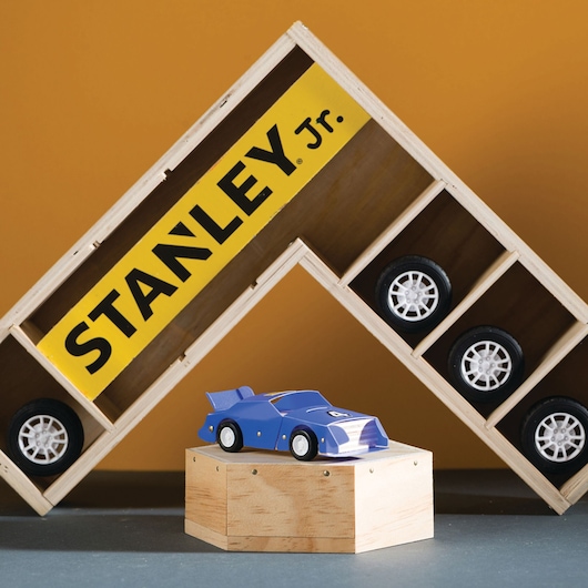 STANLEY OK013-SY wooden display shelf with toy car wheels, features a blue toy race car on a wooden stand.