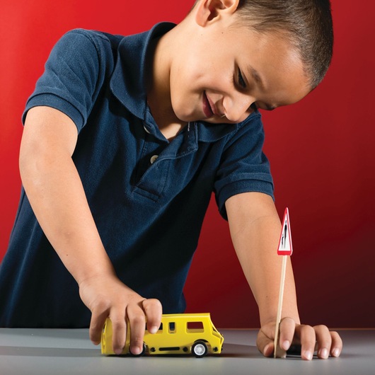 STANLEY OK015-SY photography of child in navy shirt playing with yellow toy van and small traffic sign on gray surface.