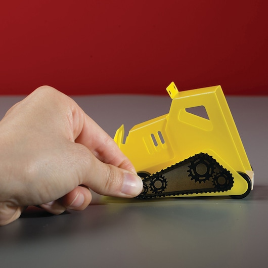 Photo of STANLEY OK017-SY yellow toy bulldozer with black gears, hand touching the track, photography product.