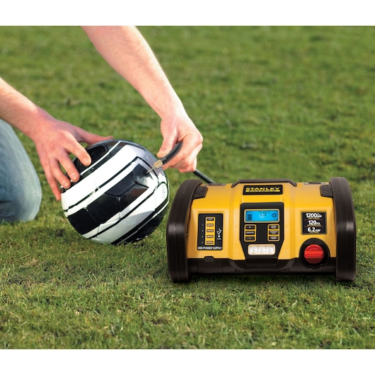 STANLEY PP1DCS portable power station inflating black and white soccer ball on grass.