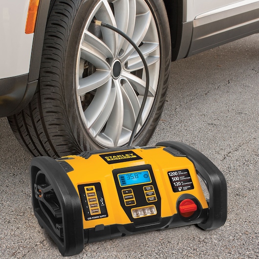 STANLEY PP1DCS portable power station inflating car tire, yellow and black unit with digital display.